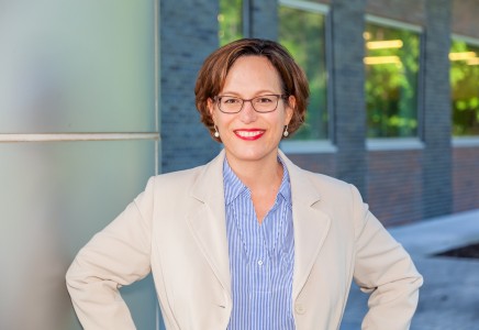 Katherine Wilson stands in front of the Technology and Engineering Development Building on the Jefferson Lab campus.