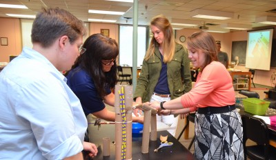 Four teachers work on a JSAT activity with paper towel rolls and pipe cleaners.