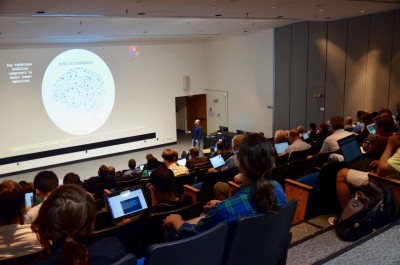JSA 2018 Postdoc Prize Winner Cristiano Fanelli, presenting research to an auditorium audience, with talk projected on wall