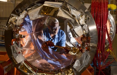 A JLab staff member makes measurements of a section of cryomodule