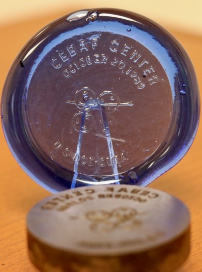 a round, flat disk made of blue glass stamped with "CEBAF Center"